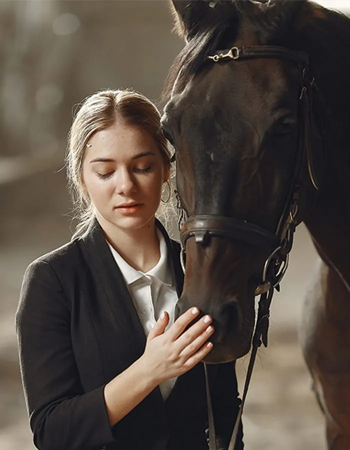 Rider in a black jacket beside her horse