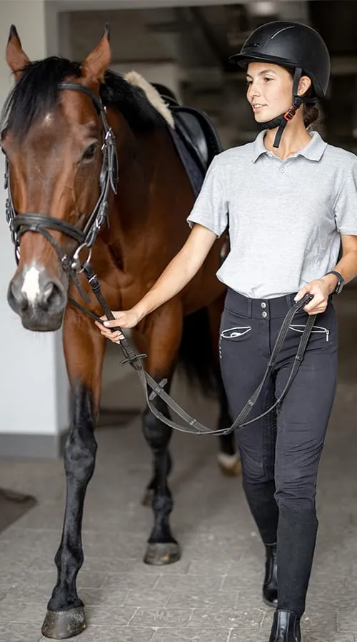 Rider leading a horse out of its stable